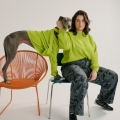 woman and greyhound sitting in chairs in matching lime green sweaters